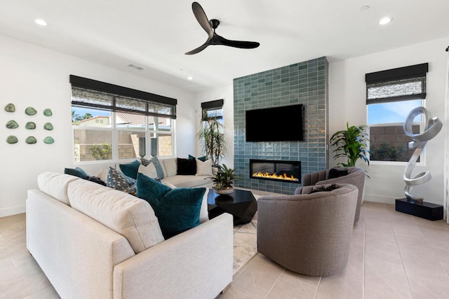 living room featuring a wealth of natural light, light tile patterned flooring, and a tiled fireplace