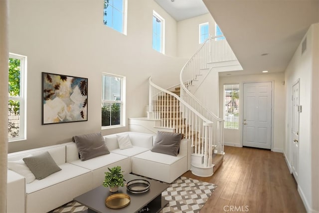 living room with hardwood / wood-style flooring and a towering ceiling