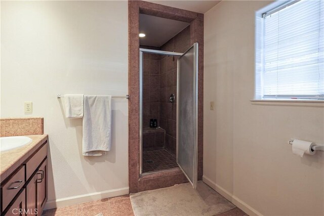 bathroom with a wealth of natural light, tile patterned flooring, vanity, and walk in shower