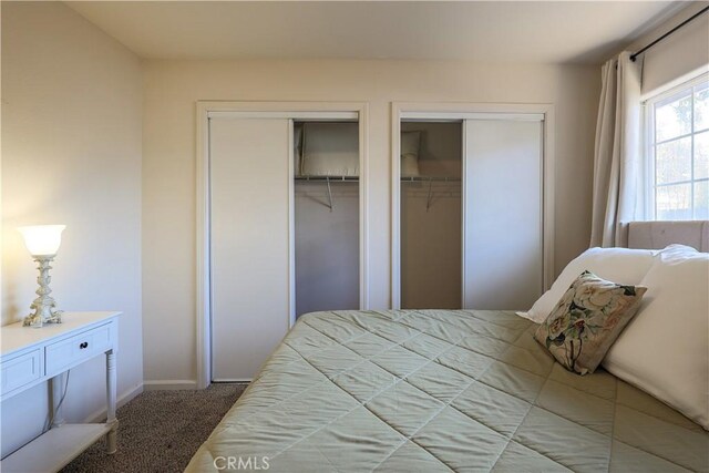 bedroom with light carpet and two closets