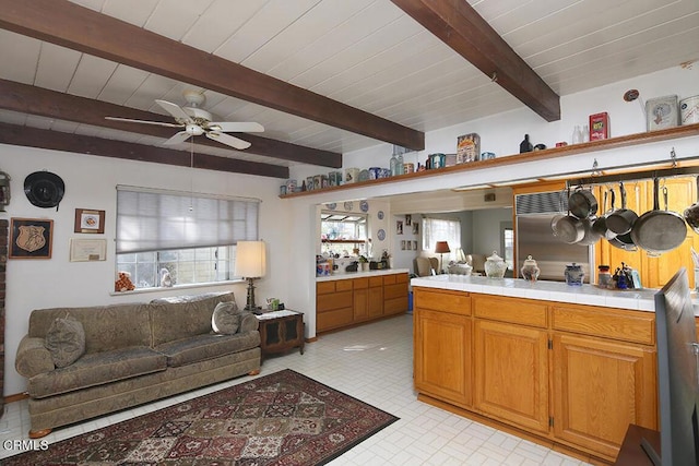 kitchen with tile countertops, ceiling fan, and beamed ceiling