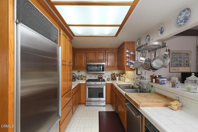 kitchen featuring backsplash, tile countertops, sink, and stainless steel appliances