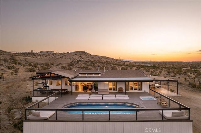 back house at dusk featuring a mountain view and a patio