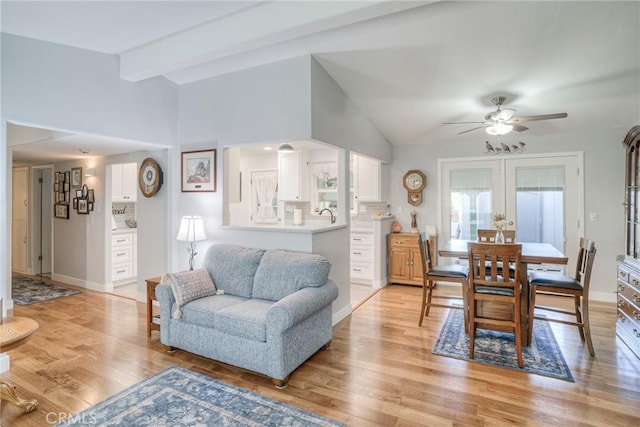 living room with sink, vaulted ceiling with beams, light hardwood / wood-style floors, and ceiling fan