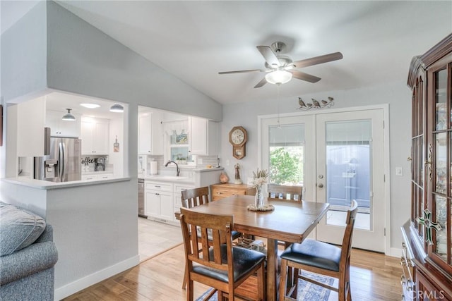 dining space with sink, light hardwood / wood-style flooring, ceiling fan, vaulted ceiling, and french doors