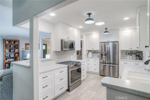 kitchen with appliances with stainless steel finishes, decorative light fixtures, decorative backsplash, and white cabinets