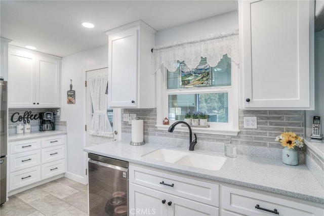 kitchen featuring sink, white cabinetry, light stone counters, stainless steel appliances, and backsplash