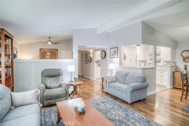 living room featuring ceiling fan, vaulted ceiling, and light hardwood / wood-style flooring