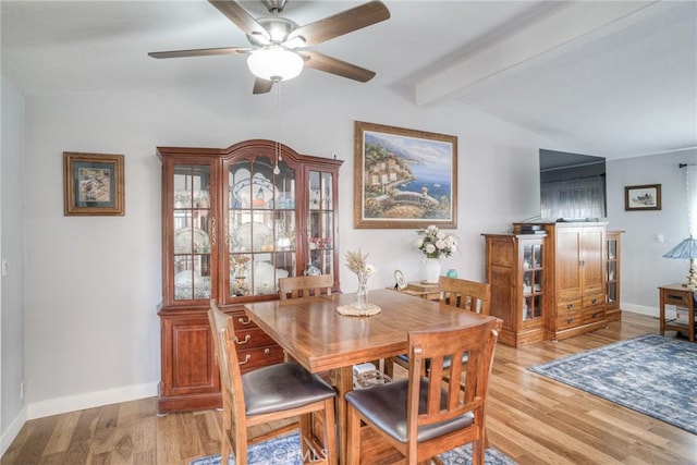 dining space featuring ceiling fan, light hardwood / wood-style flooring, and vaulted ceiling with beams