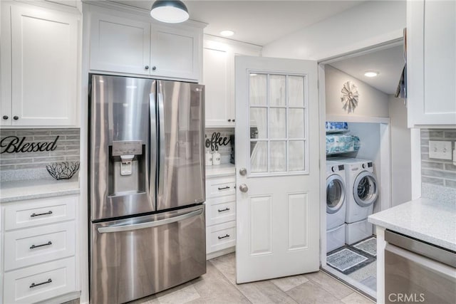 kitchen with white cabinetry, tasteful backsplash, light tile patterned floors, appliances with stainless steel finishes, and washer and clothes dryer