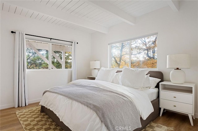 bedroom featuring beamed ceiling, dark hardwood / wood-style flooring, and multiple windows