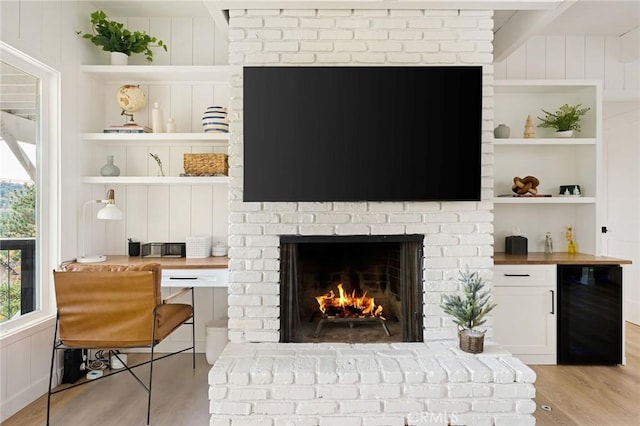 living room featuring light hardwood / wood-style flooring, built in features, a brick fireplace, beverage cooler, and wood walls