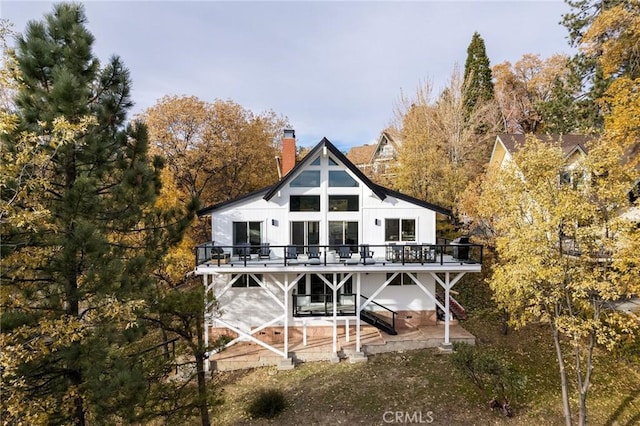 back of property featuring a wooden deck and a patio