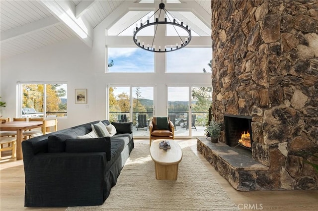 living room with an inviting chandelier, a fireplace, beam ceiling, and light hardwood / wood-style flooring