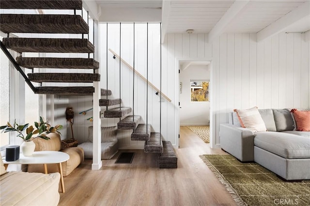 staircase featuring wood-type flooring, wooden walls, and beamed ceiling