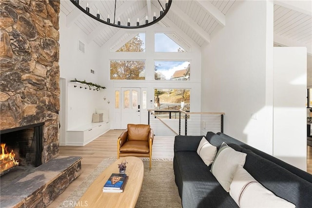 living room featuring hardwood / wood-style flooring, a stone fireplace, high vaulted ceiling, and beamed ceiling