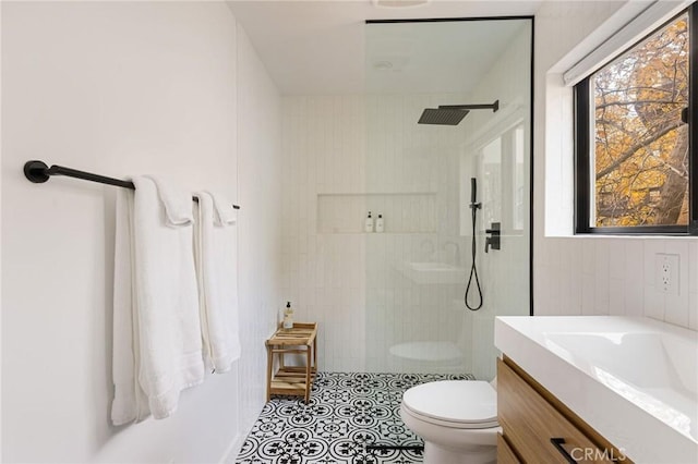 bathroom with vanity, tiled shower, and toilet