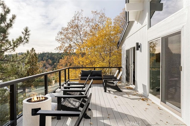 wooden terrace featuring an outdoor living space with a fire pit