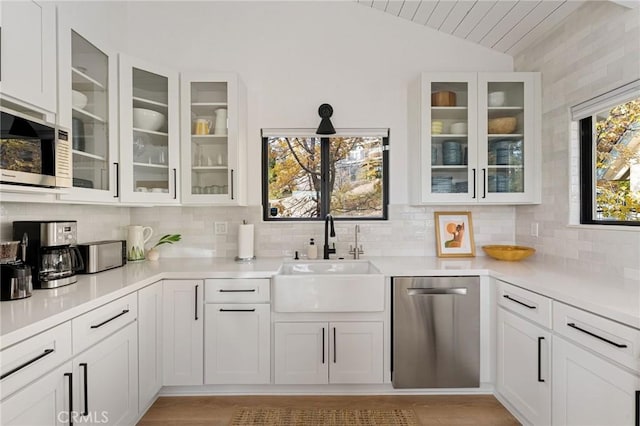 kitchen featuring dishwasher, white cabinetry, lofted ceiling, and sink