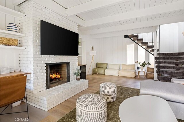 living room featuring a fireplace, beam ceiling, and wood-type flooring