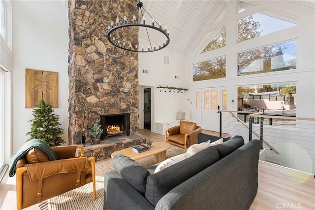 living room featuring a stone fireplace, high vaulted ceiling, and light hardwood / wood-style floors