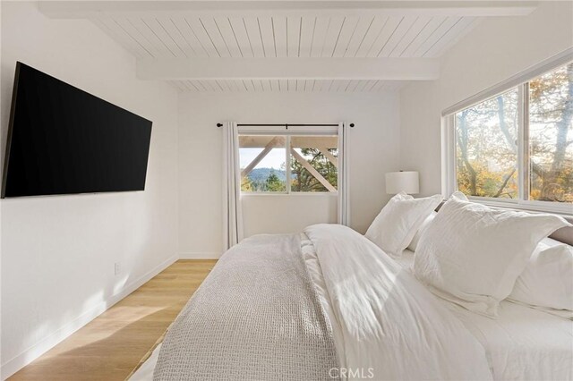 bedroom featuring beam ceiling and light hardwood / wood-style floors