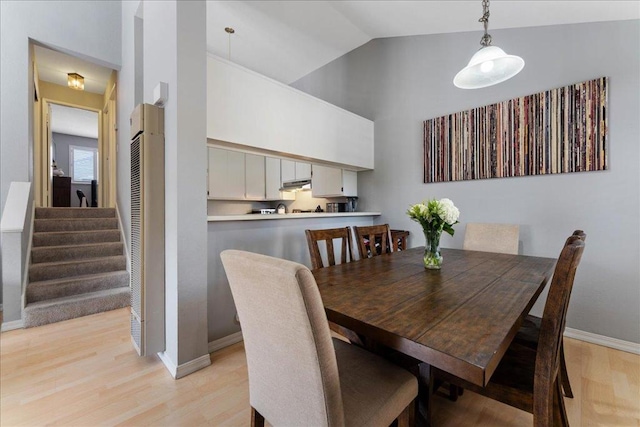 dining room with high vaulted ceiling and light wood-type flooring