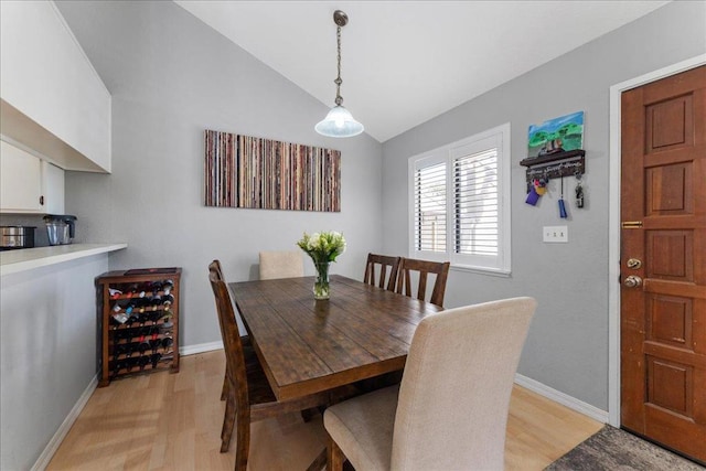 dining space featuring wine cooler, lofted ceiling, and light hardwood / wood-style floors