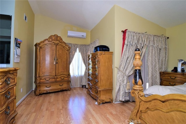 bedroom featuring an AC wall unit, vaulted ceiling, and light wood-type flooring