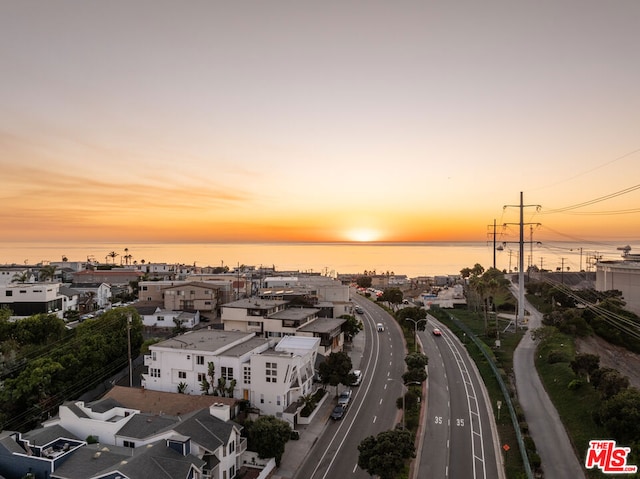 aerial view at dusk featuring a water view