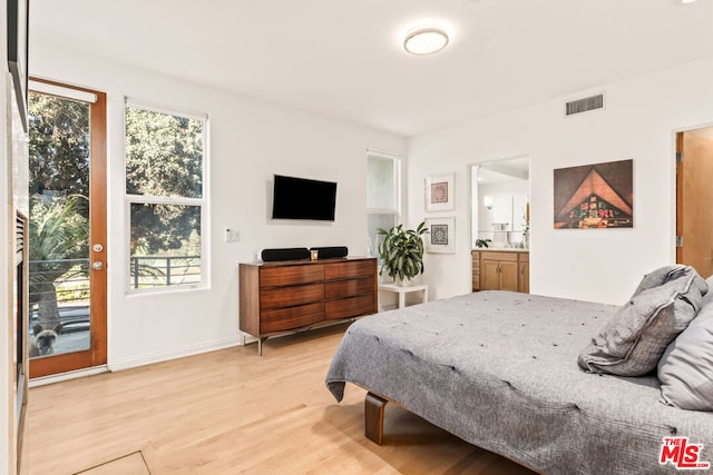 bedroom featuring ensuite bathroom, light wood-type flooring, and access to outside