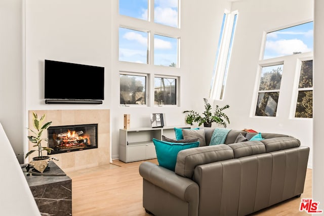 living room with plenty of natural light, light wood-type flooring, and a high ceiling