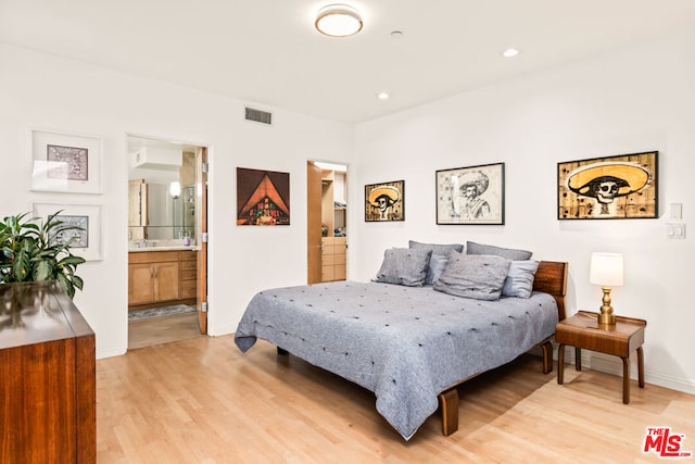 bedroom featuring connected bathroom and light hardwood / wood-style flooring