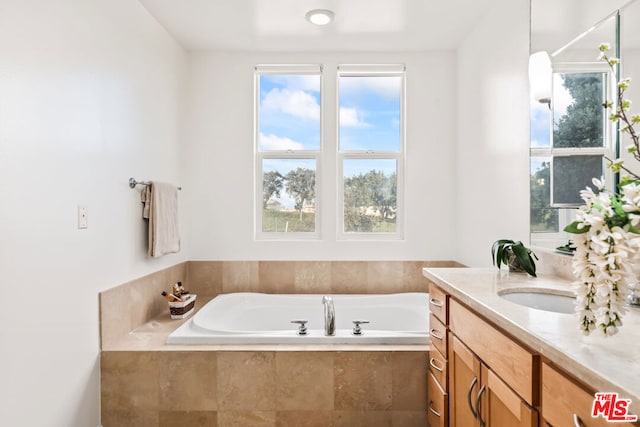 bathroom with tiled tub and vanity