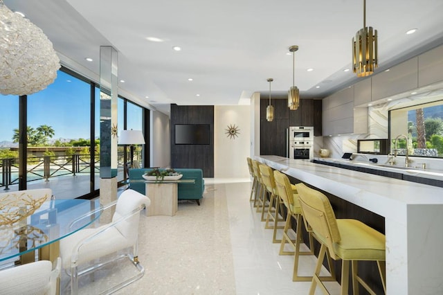 kitchen featuring a kitchen bar, a notable chandelier, pendant lighting, and backsplash