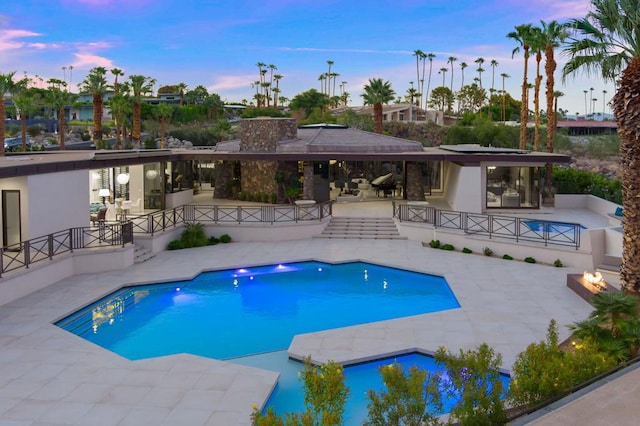 pool at dusk with a patio area