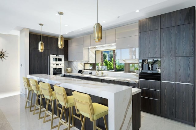 kitchen featuring hanging light fixtures, a large island, a breakfast bar, sink, and tasteful backsplash