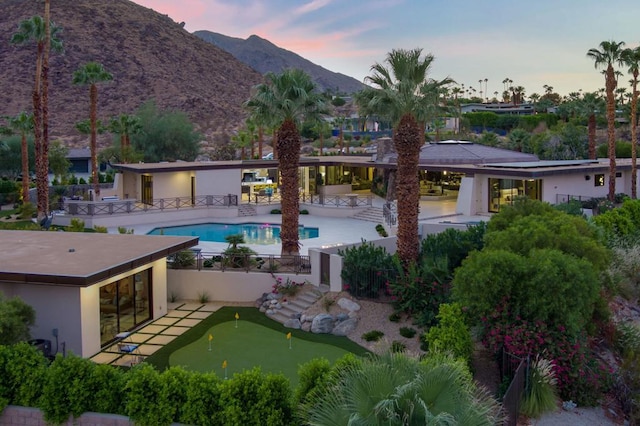 pool at dusk featuring a mountain view and a patio area