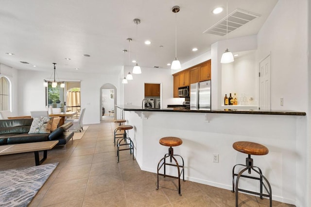 kitchen with a breakfast bar, decorative light fixtures, stainless steel appliances, and light tile patterned floors