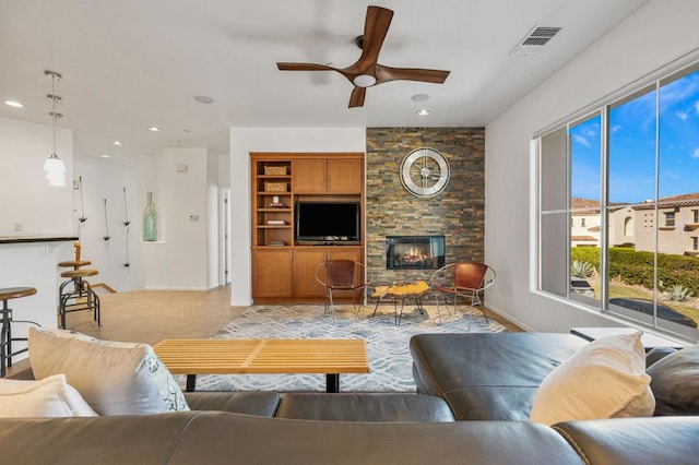 living room with ceiling fan and a fireplace