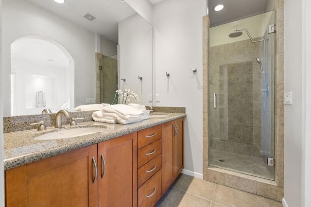 bathroom with tile patterned flooring, vanity, and walk in shower