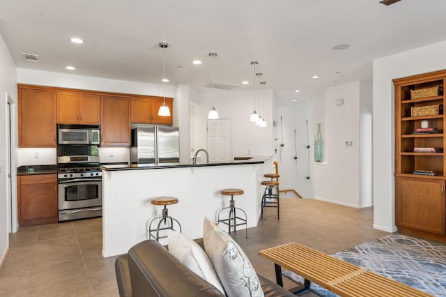 kitchen with a kitchen breakfast bar, stainless steel appliances, light tile patterned floors, decorative light fixtures, and a center island with sink