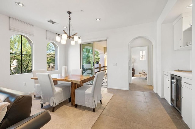 dining room featuring a chandelier, light tile patterned flooring, and beverage cooler