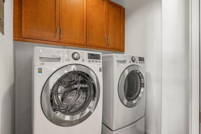 laundry area featuring washer and clothes dryer and cabinets