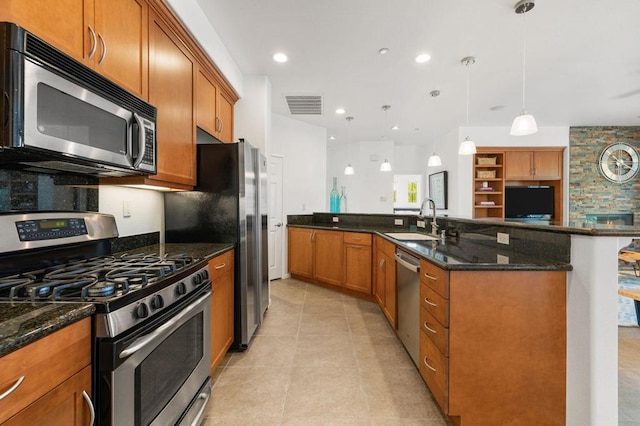 kitchen featuring sink, dark stone countertops, light tile patterned floors, decorative light fixtures, and stainless steel appliances