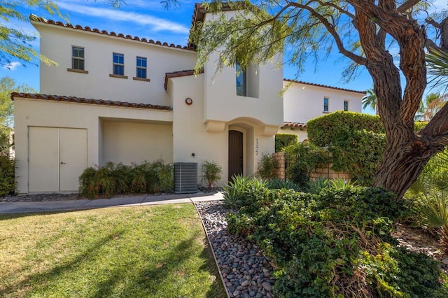 mediterranean / spanish house featuring central air condition unit and a front yard