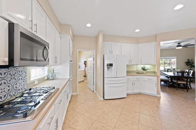 kitchen with appliances with stainless steel finishes, light tile patterned floors, white cabinetry, and ceiling fan