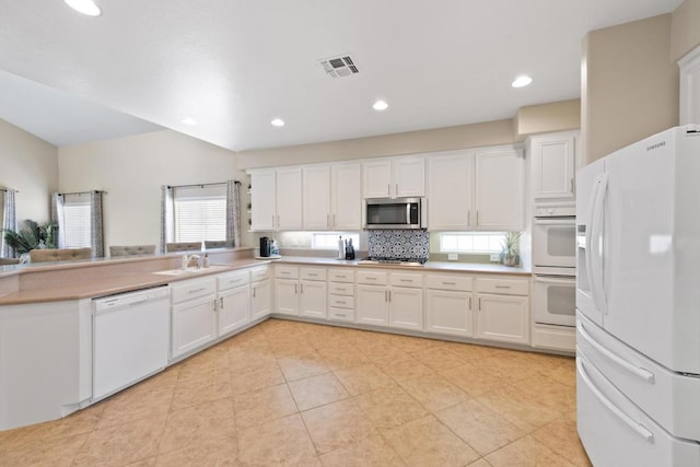 kitchen with sink, stainless steel appliances, light tile patterned floors, backsplash, and white cabinets