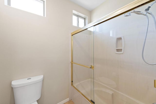 bathroom featuring toilet and combined bath / shower with glass door