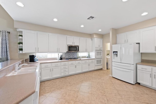 kitchen featuring white cabinetry, sink, backsplash, light tile patterned floors, and appliances with stainless steel finishes